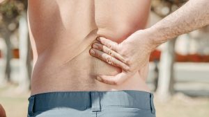 man holding his lower back, likely experiencing back pain