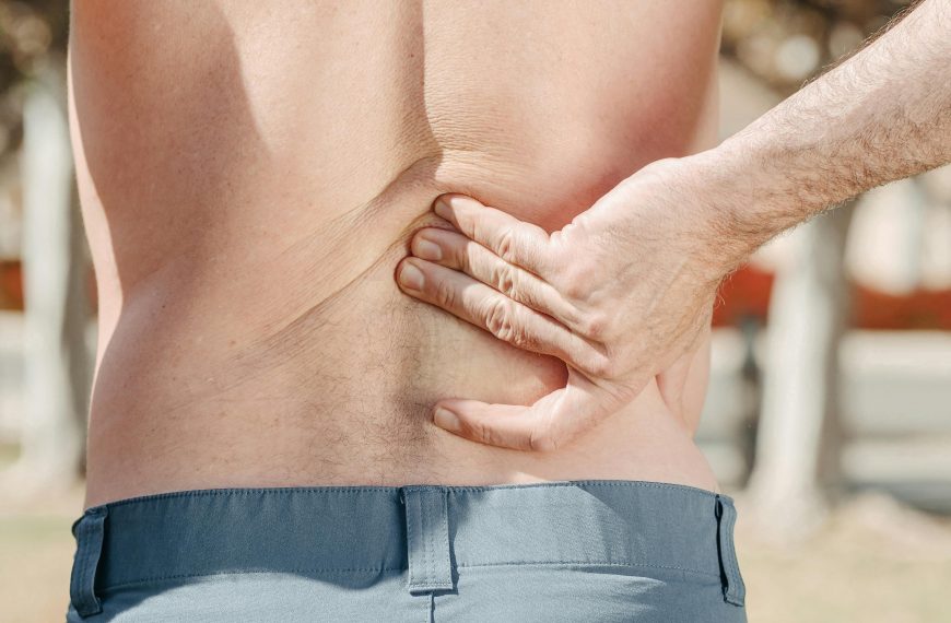 man holding his lower back, likely experiencing back pain