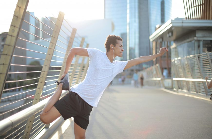 man wearing running gear and earphones doing a pre-run stretch