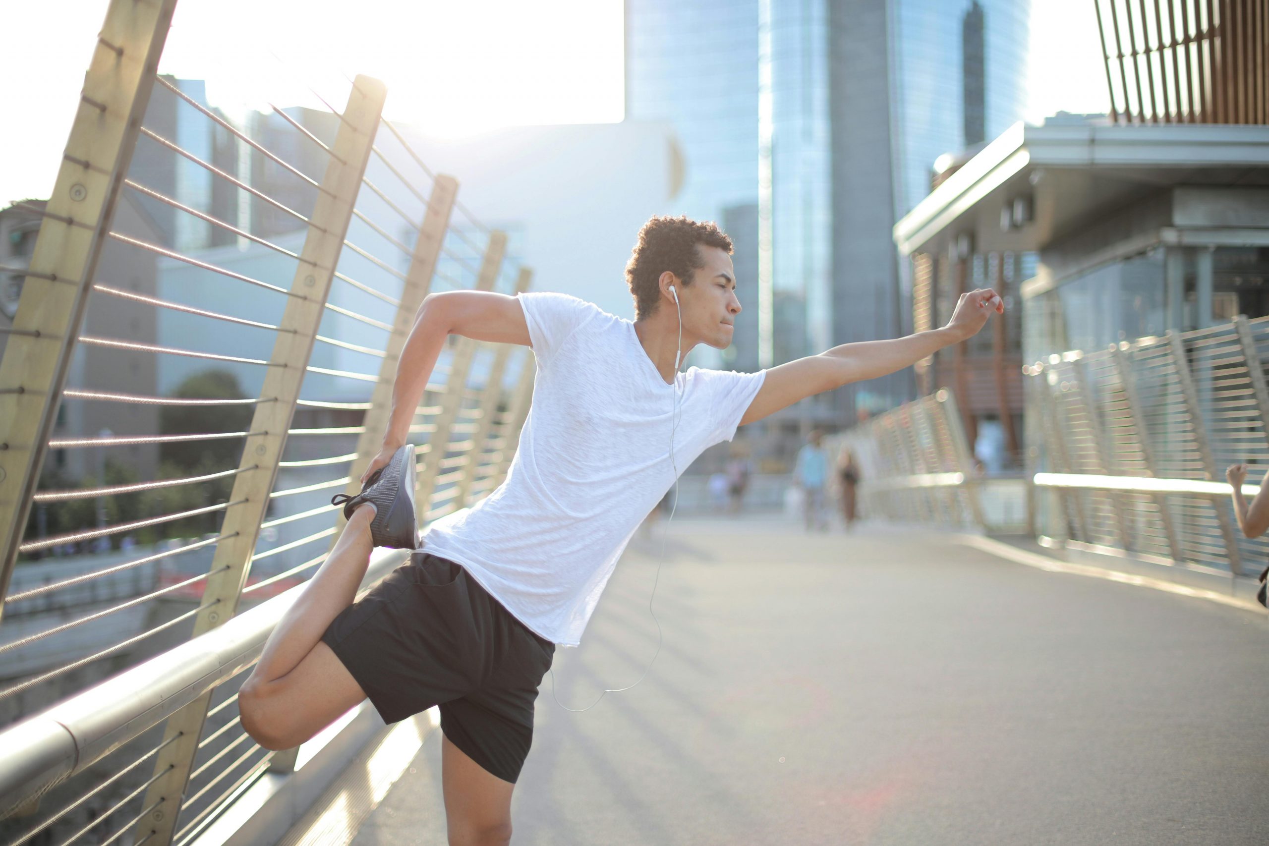 man wearing running gear and earphones doing a pre-run stretch